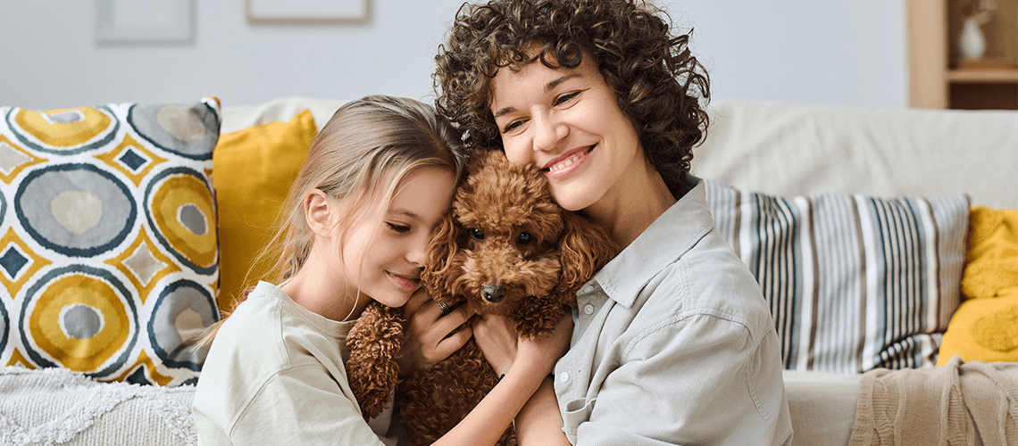Celebrating-Mother’s-Day-with-Your-Furry-CompanionBlog-Banner woman and girl cuddling dog